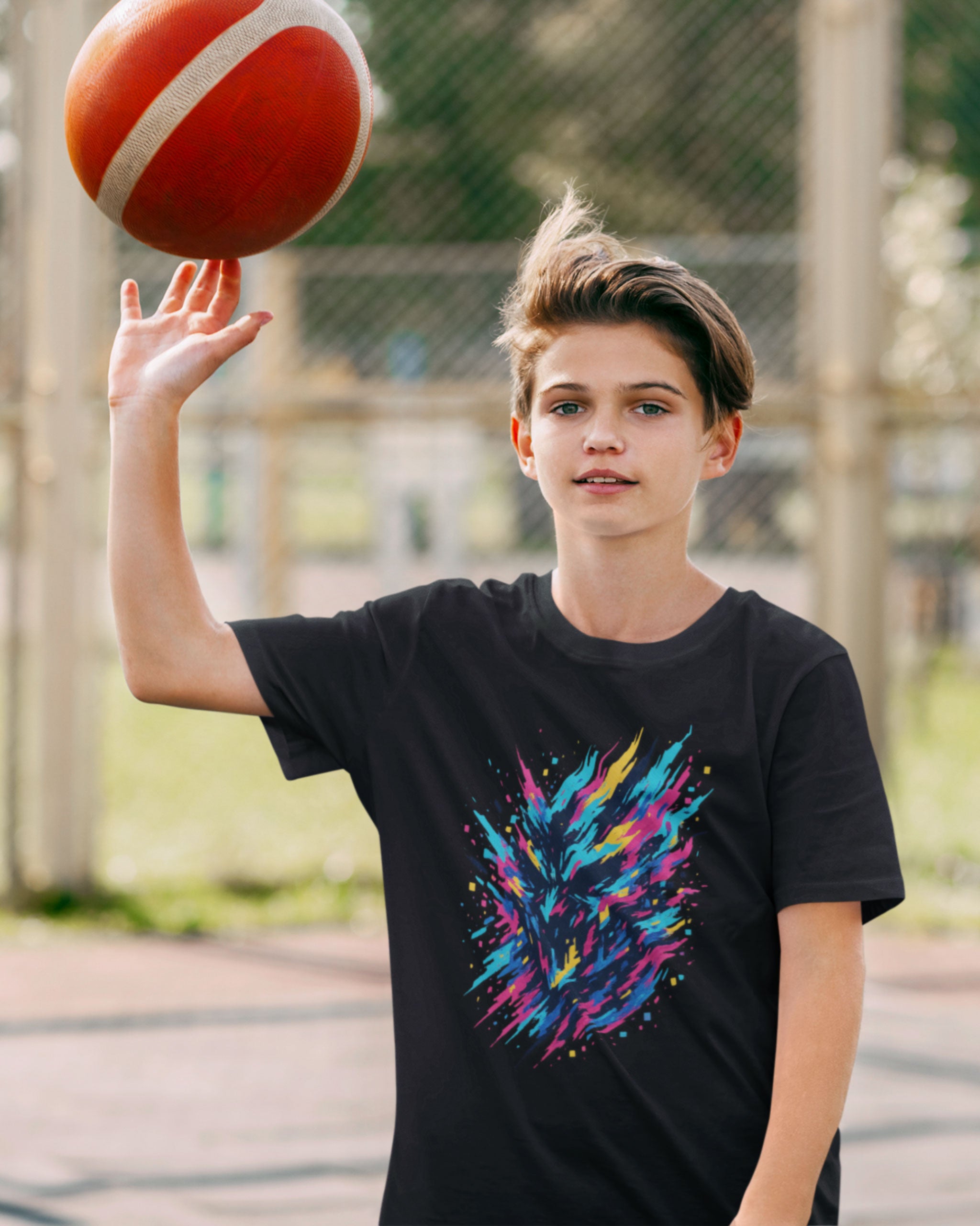 Youth wearing black glitch burst graphic tee while spinning a basketball — vibrant streetwear design in neon blue, pink, yellow, and purple.